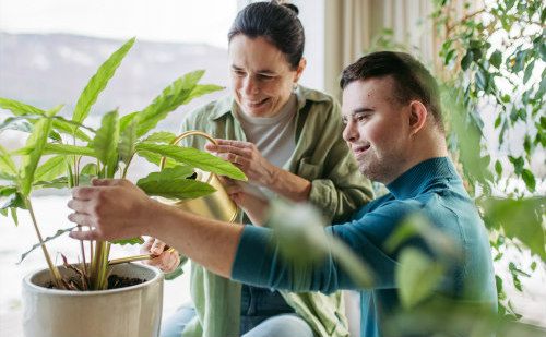 Carer and disabled child with Down Syndrome looking at plants